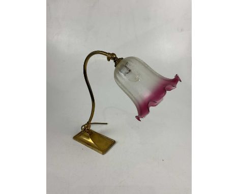 An early 20th century brass adjustable reading lamp, with cranberry and frosted glass shade, height 33cm.