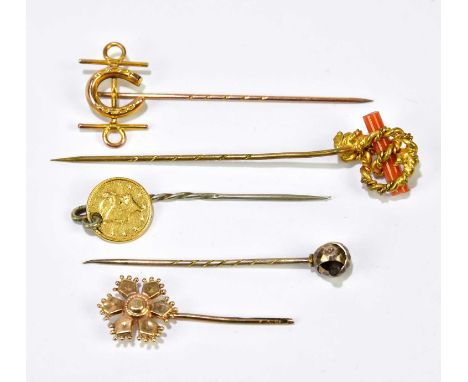 A Victorian yellow metal stick pin set with a horseshoe, three further stick pins and a silver metal stick pin set with a gol