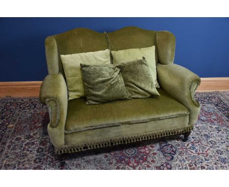 An early 20th century wingback two seater sofa, with green upholstery, on turned and block legs and stretcher, height 98cm, l