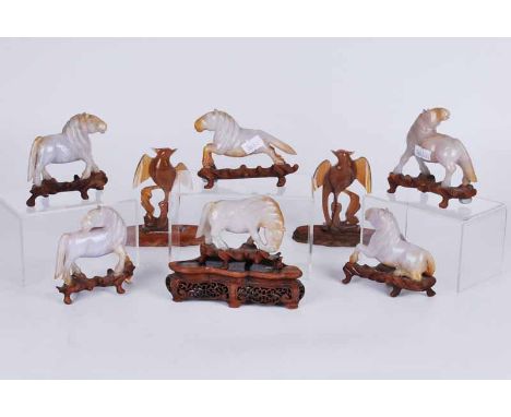 A group of early 20th century carved jade horses in celedon and russett colouration, on carved wooden stands, plus a pair of 