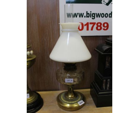 AN EARLY 20TH CENTURY BRASS BASED OIL LAMP with clear reservoir and milk glass shade