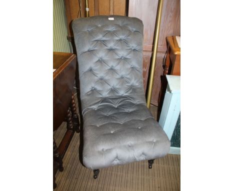 A 19TH CENTURY BLUE VELOUR UPHOLSTERED BUTTONED SLIPPER CHAIR supported on short ebonised legs with ceramic castors below 