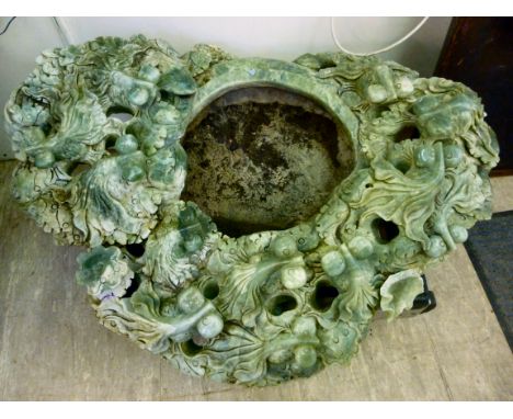 An Oriental carved jade coloured stone fish pond, the 15''dia bowl having a wide border, featuring specimen fish and stylised