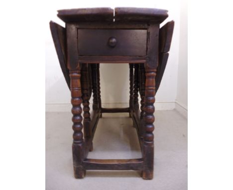 An early/mid 18thC and later country made oak gateleg table, the planked, oval top, over an end drawer, raised on bobbin turn