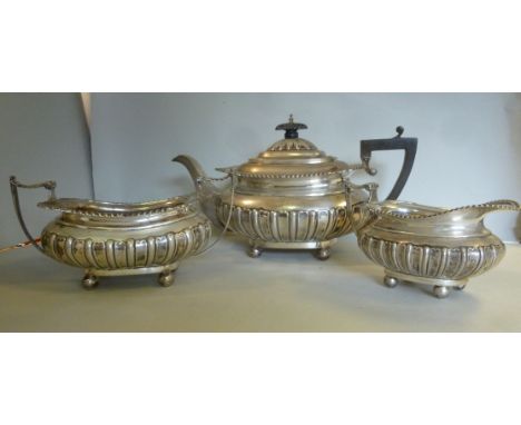 An Edwardian three piece silver tea set of oval, ogee form with demi-reeded and fluted, gadrooned and shell cast ornament, co