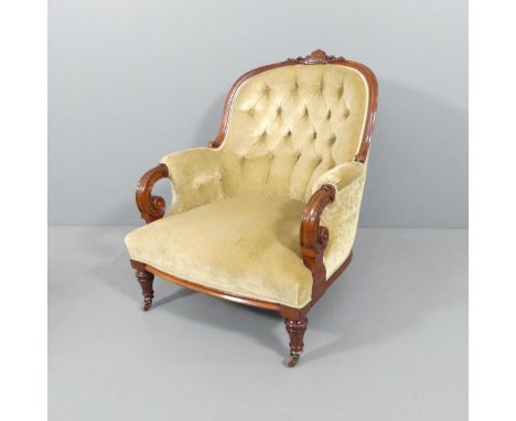 A Victorian mahogany and button back upholstered arm chair, with carved decoration. 