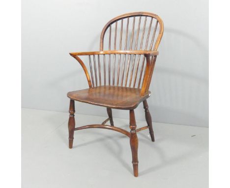 An antique elm-seated comb-back Windsor elbow chair with crinoline stretcher. Overall 57x95x56cm, seat 38x44x41cm.Slightly lo