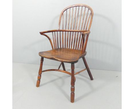 An antique elm-seated comb-back Windsor elbow chair with crinoline stretcher. Overall 59x102x56cm, seat 40x46x41cm.Good condi