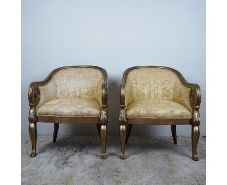 A pair of elegant and comfortable Neoclassical-style armchairs featuring intricately carved giltwood frames and luxurious dam