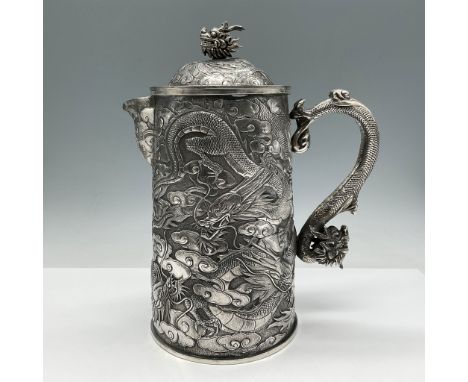 Ornate silver tankard features elaborate repousse and chased designs of sinuous dragons among swirling clouds, symbols of pow