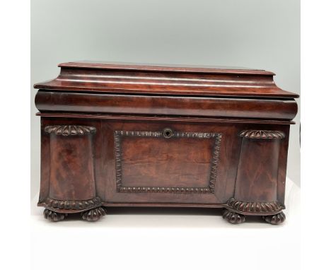 A finely crafted antique mahogany tea caddy featuring a domed lid and elaborately carved decorative accents. The caddy is des