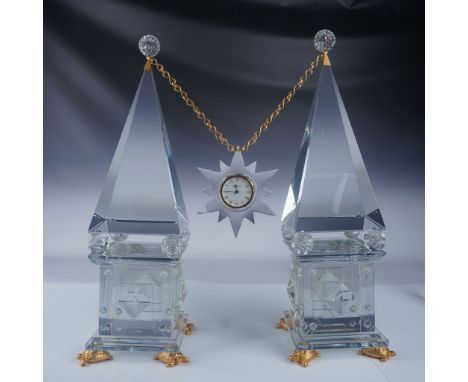 An exceptional Baccarat crystal clock set featuring two obelisk towers and a hanging starburst clock suspended on a gold-tone