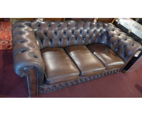 A three seater brown leather Chesterfield sofa. 