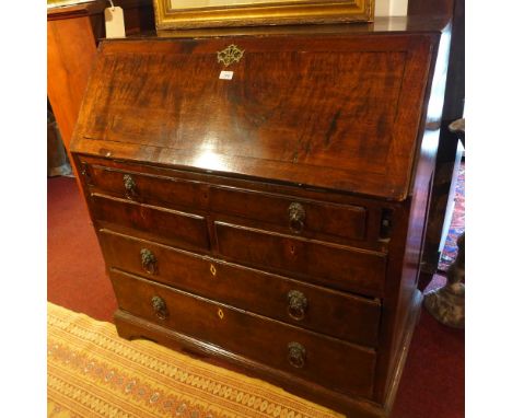 A Georgian oak bureau with drop down flap above five drawers, raised on carved bracket feet. 