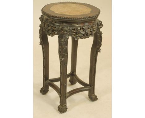 A CHINESE HARDWOOD JARDINIERE STAND, c.1900, of lobed circular form, the headed edged top with inset red marble, pierced scro