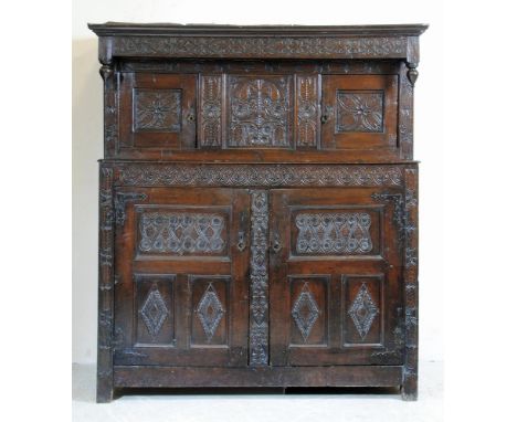 AN OAK PRESS CUPBOARD, mid to late 17th century, the canopy with moulded cornice and strapwork carved frieze having turned pe