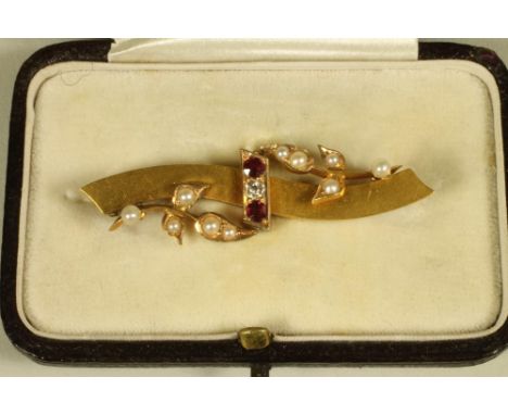 A LATE VICTORIAN 15CT GOLD BROOCH, the wide wavy bar centred by a gypsy set diamond horizontally flanked by two rubies and wi