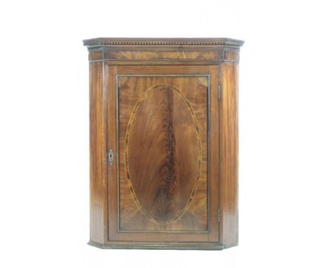A GEORGIAN MAHOGANY CORNER CUPBOARD, late 18th century, the dentil moulded cornice over a single door with crossbanded oval p
