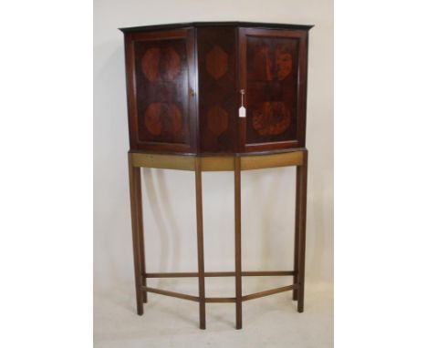 A LATE VICTORIAN MAHOGANY CABINET ON STAND, of canted form with ebony stringing, the moulded edged cornice over two panels ea