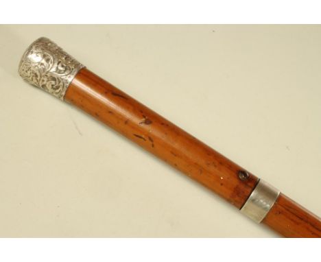 A VICTORIAN SWORD STICK, the button release 26 ¾" blade with blued scroll decoration, housed in a malacca cane with an emboss