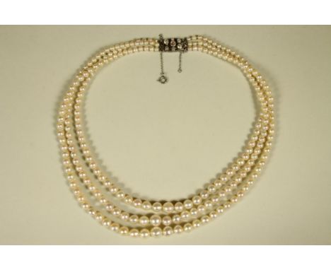A GRADUATED TRIPLE STRAND CULTURED PEARL NECKLACE, the 18ct white gold and platinum clasp collet set with seven mixed cut dia