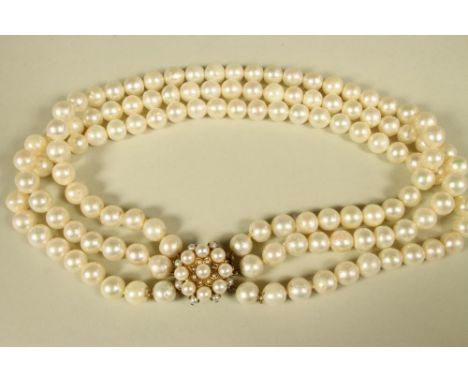 A TRIPLE STRAND CULTURED PEARL NECKLACE, with pearl set flower head 9ct gold clasp