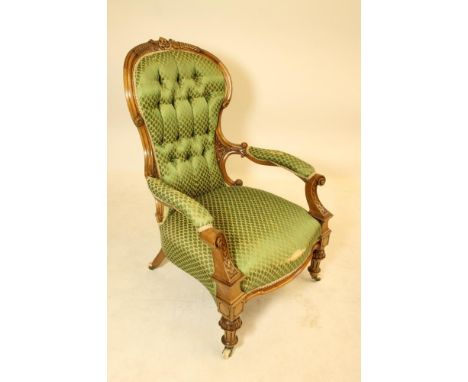 A VICTORIAN CARVED WALNUT SALON CHAIR of spoon back form button upholstered in green silk damask, channelled frame, waisted b