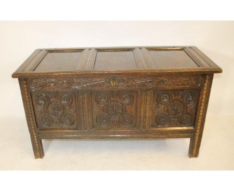 A CARVED OAK PANELLED COFFER, c.1700, with triple panel hinged lid, the fascia with foliate carved frieze over three panels w