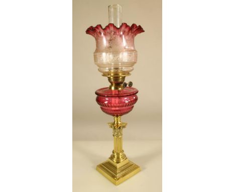 A VICTORIAN BRASS OIL LAMP BASE, the short Corinthian column on a stepped square base supporting a printe cut cranberry glass