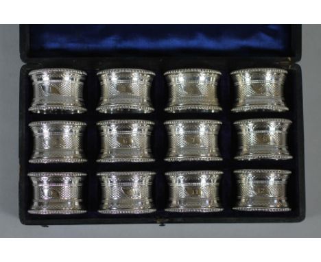 A SET OF TWELVE LATE VICTORIAN EPNS NAPKIN RINGS of waisted cylindrical form with bead cast borders and engine turned centre 