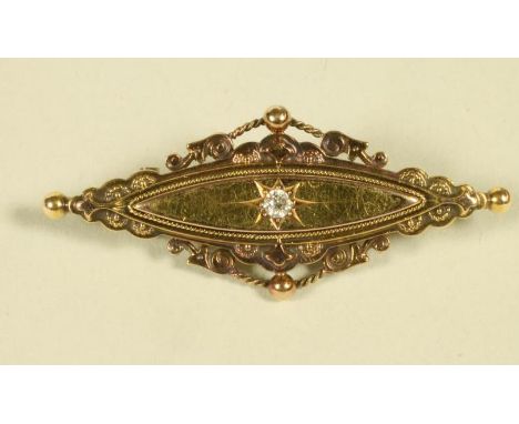A LATE VICTORIAN 15CT GOLD BROOCH, the eliptical panel centred by a gypsy set diamond within filigree borders, with glazed pa