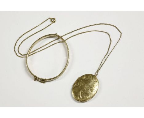 A gold front and back oval locket, with engraved decoration on a 9ct gold chain,  and a rolled gold bangle