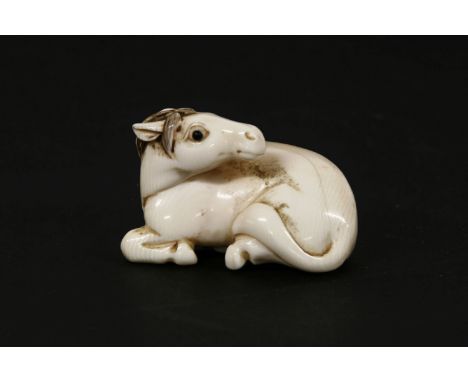 A Japanese ivory netsuke of a horse lying down, c.1920. Signed. 5cm long