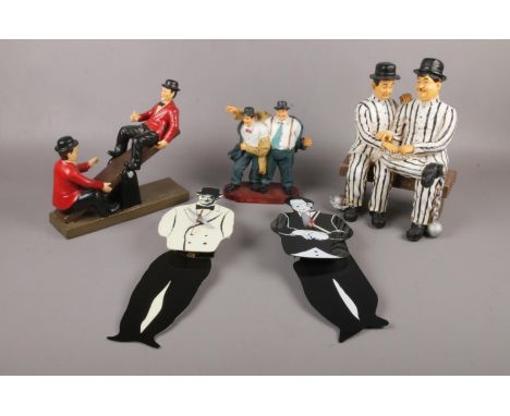 A group of Laurel &amp; Hardy ceramic figures, sat on a see- saw,  in prison uniform, to include swing wall clocks etc  