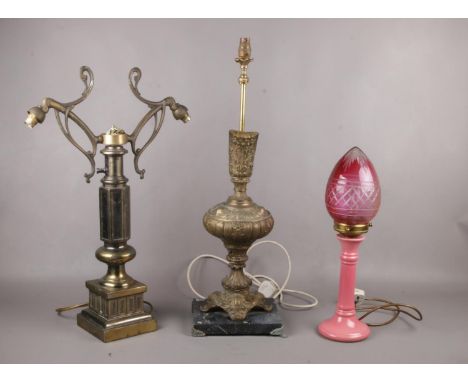 Three table lamps,  two ornate brass lamps and ceramic pink lamp with cranberry glass shade  