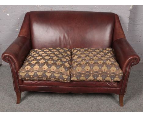 A tanned leather two seat sofa with studded arms. (84cm x 144cm)  