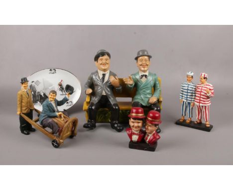 A group of Laurel &amp; Hardy ceramic figures, sat on bench, with jail clothing on, on suitcase trolley, wall clock examples 