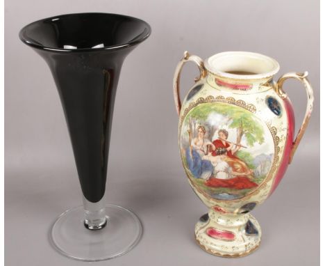A large black glass art vase along with a ceramic twin handled vase depicting figures.  
