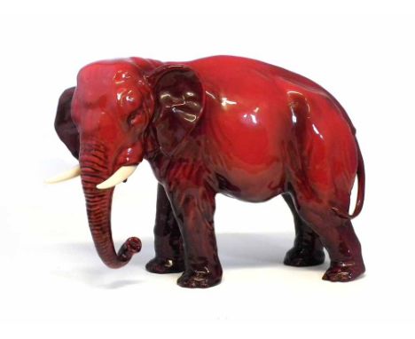 Large Royal Doulton flambé elephant, modelled with trunk curled down with two ivory coloured tusks signed Noke to one foot, 3