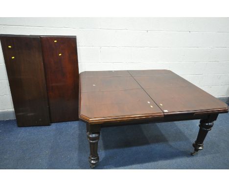 A LATE VICTORIAN MAHOGANY WIND OUT DINING TABLE, on turned fluted legs, brass caps and ceramic casters, with two additional l