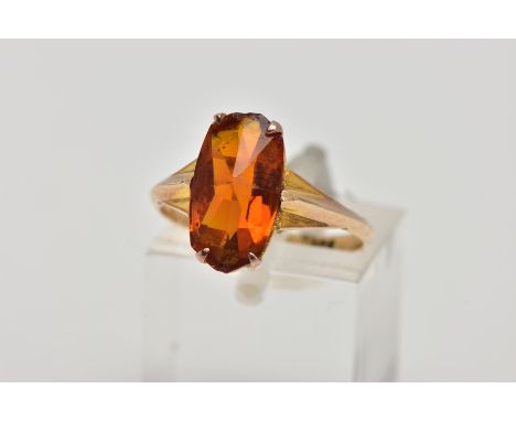 A YELLOW METAL RING, designed with a four claw set, fancy rectangular cut orange stone assessed as paste, to a yellow metal k