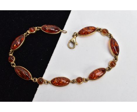 A 9CT GOLD AMBER LINE BRACELET, designed with seven bezel mounted amber cabochons of a marquise shape, interspaced with bezel