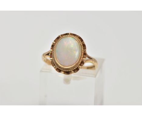 A 9CT GOLD OPAL DRESS RING, designed as an oval cabochon within a collet mount, swag surround, bifurcated shoulders to a plai