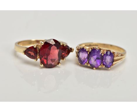 TWO 9CT GOLD GEM SET RINGS, the first designed with a central four claw set, oval cut garnet, flanked with triangular cut gar