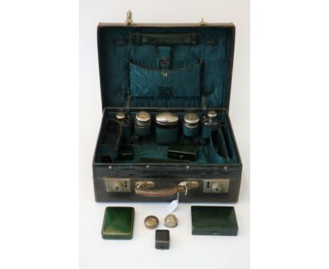 A late Victorian leather toilet case containing five silver topped faceted glass bottles and jars, the lids London 1899, anot