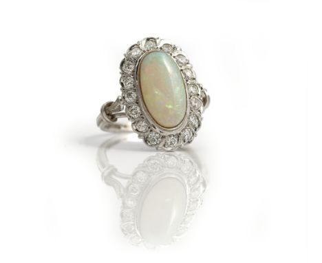 A white gold, opal and diamond set oval cluster ring, collet set with the oval opal at the centre, in a surround of circular 