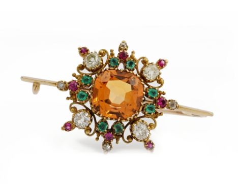 A late 19th/early 20th entury topaz, emerald, ruby and diamond brooch, the central cushion cut topaz claw set in a surround o