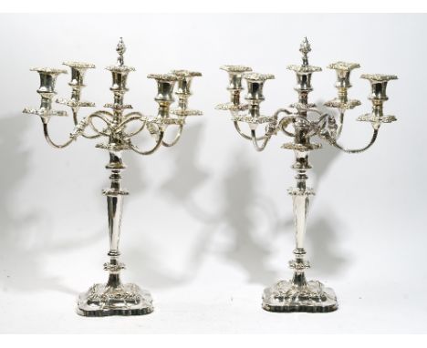 A pair of silver plated on copper five light table candelabra, with scrolling arms, decorated borders, the central light havi