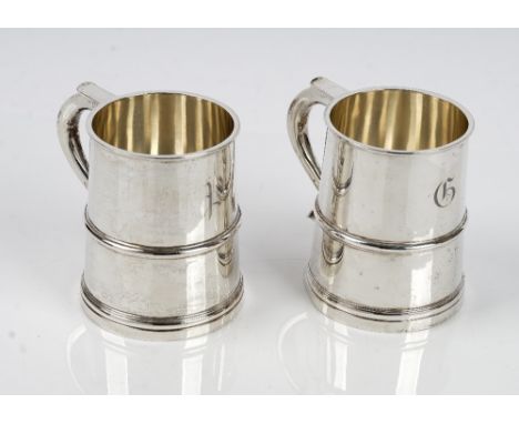 A pair of silver mugs, each of tapered cylindrical form in the 18th century taste, the handles having heart shaped terminals,