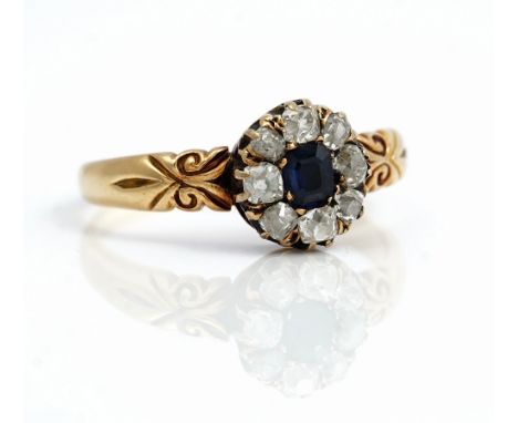 A gold, sapphire and diamond nine stone cluster ring, mounted with a step cut sapphire at the centre in a surround of eight c